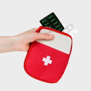 a hand holding a red and white first aid kit