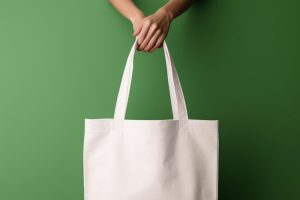 Hands holding a Canvas Tote Bag in a green background