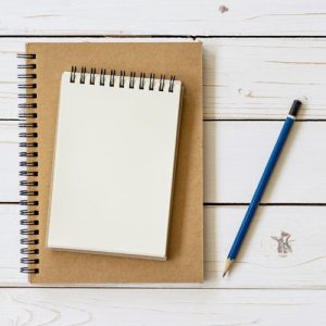 Open notebook with blank pages and pencil